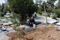 A relative reads Koran after burial of the journalist Abdollah Zavieh, who passed away due to coronavirus disease (COVID-19), at Behesht Zahra cemetery in Tehran