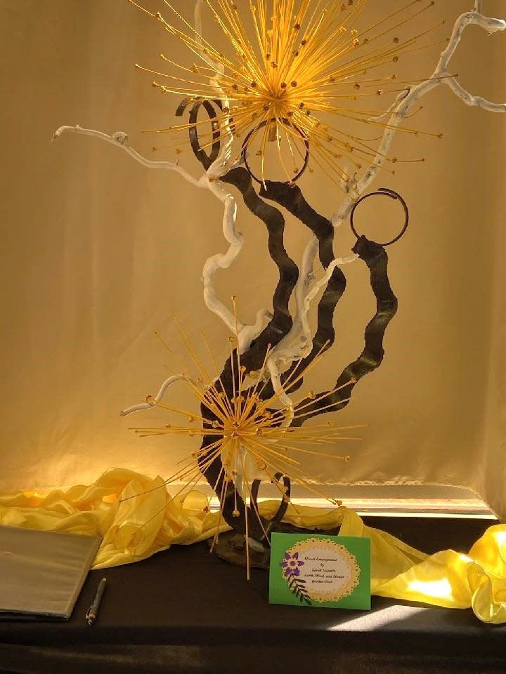 Two yellow Schubertii allium heads appear in Sarah Laipply's sculpted container design for the eclipse. Twigs painted white suggest beams of leaking sunlight.