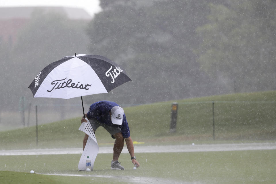 Equipment is picked up off the practice green as rain falls at the World Golf Championship-FedEx St. Jude Invitational Wednesday, July 29, 2020, in Memphis, Tenn. (AP Photo/Mark Humphrey)