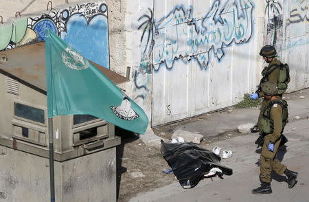 Israeli soldiers stand next to the body of a Palestinian, who Israeli police and army said stabbed a soldier, after he was shot by an Israeli policeman, in the West Bank old city of Hebron October 29, 2015. REUTERS/Mussa Qawasma