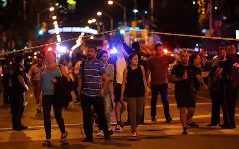 People leave an area taped off by the police near the scene of a mass shooting in Toronto - Credit: CHRIS HELGREN /Reuters