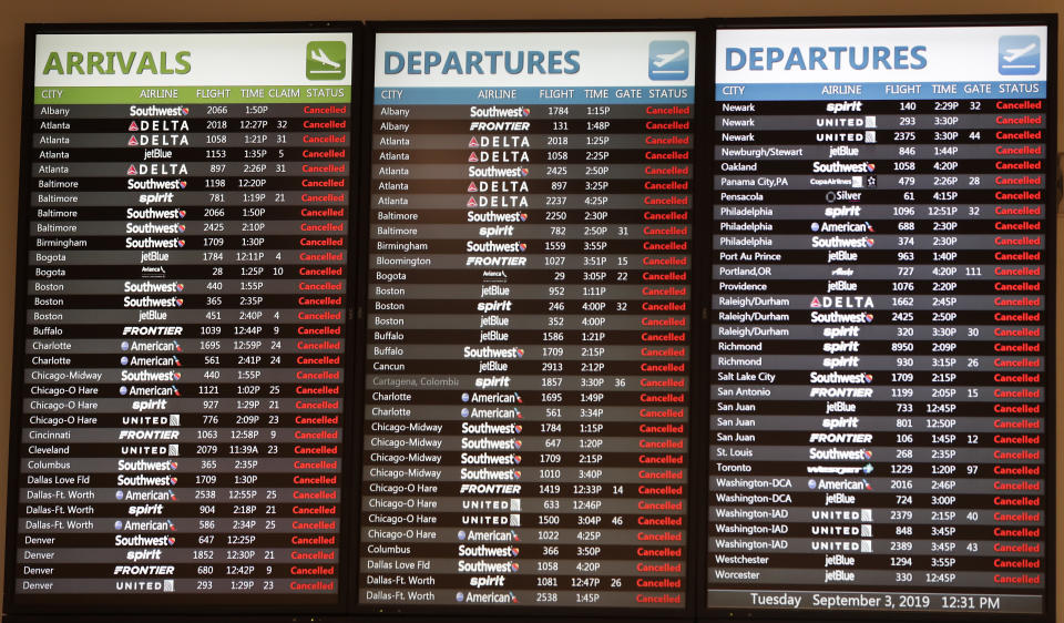 Flight information monitors show all flights cancelled as Orlando International Airport closed due to the anticipated arrival of Hurricane Dorian on the East Coast Tuesday, Sept. 3, 2019, in Orlando, Fla. (AP Photo/John Raoux)