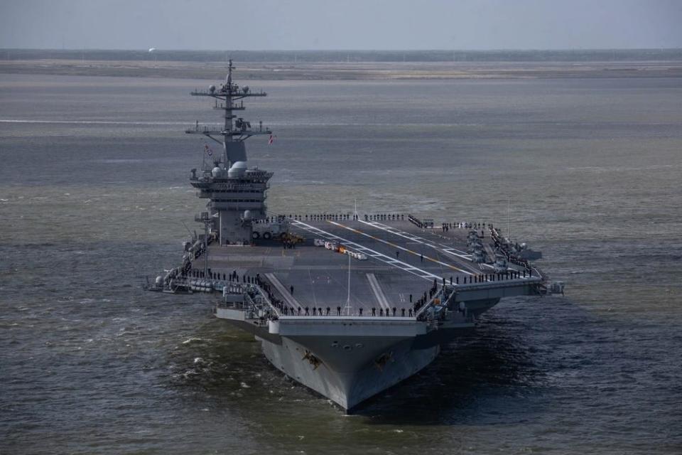 A front view of the Nimitz-class aircraft carrier USS George Washington with sailors lining the edge of the flight deck.