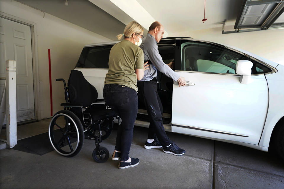 Health aide Angela Martin helps former Detroit Red Wings star Vladimir Konstantinov into a vehicle Tuesday, May 17, 2022, in West Bloomfield, Mich. Konstantinov is in danger of losing the 24/7 care he has had for two-plus decades. The disabled former NHL defenseman is a casualty of changes to Michigan's auto insurance law that curbed or cut what hospitals, residential care facilities and home providers can charge car insurers for care. Konstantinov suffered a severe brain stem injury from an accident in a limousine with an impaired driver after a Stanley Cup celebration nearly 25 years ago. (AP Photo/Carlos Osorio)