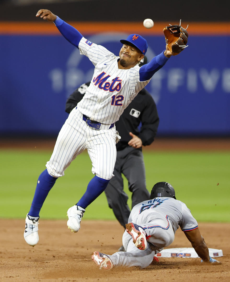 Miami Marlins' Otto Lopez (61) steals second base after a throwing error to New York Mets shortstop Francisco Lindor (12) during the ninth inning of a baseball game, Tuesday, June 11, 2024, in New York. (AP Photo/Noah K. Murray)