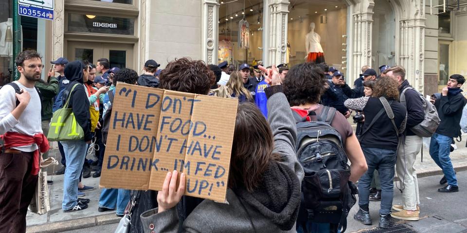 A group of protesters hold signs and march outside.