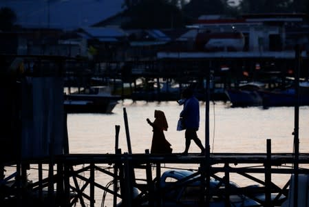 A muslim girl walks through a wooden bridge near a port in North Penajam Paser regency, East Kalimantan province