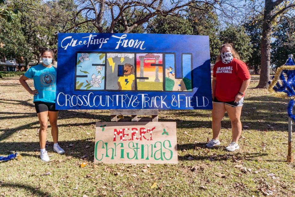 Freshmen track athletes Jessie Sanchez (Stillwell, Oklahoma) and Sammy Wallis (Pottsboro, Texas) display lawn decorations from the Southeastern cross country and track teams at the SOSU loop of lights in 2020.