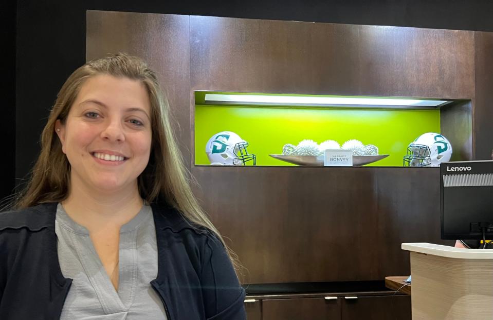 Christine Forrest, sales manager for the Courtyard by Marriott in downtown DeLand, is pictured in front of the hotel's lobby where Stetson University football helmets are on display. (June 7, 2023.)