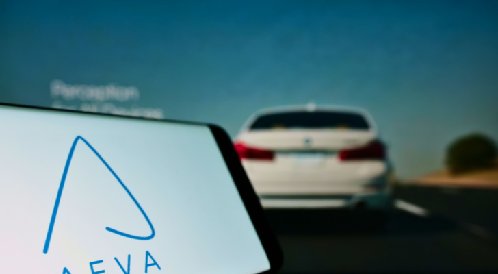 Mobile phone with logo of American autonomous driving company Aeva Inc. on screen in front of business web page. Focus on left of phone display. Unmodified photo.