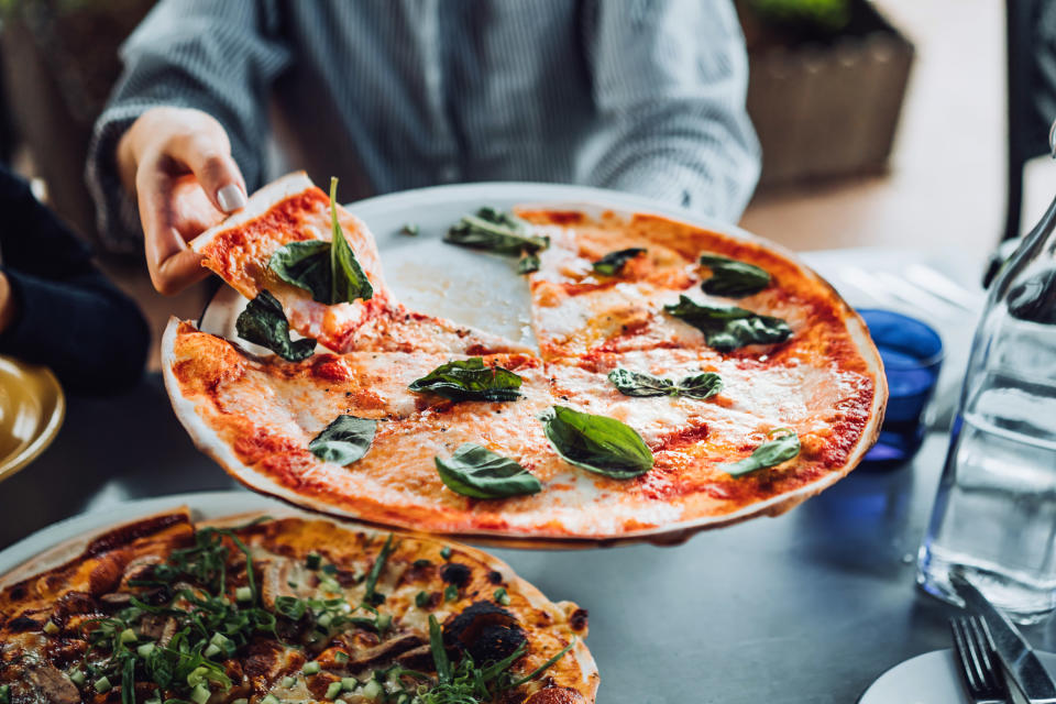 a pizza being held above a table in a restaurant