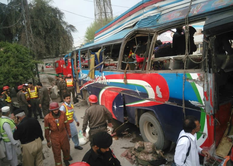 Pakistani police officials search a damaged bus after a bomb blast in Peshawar on March 16, 2016
