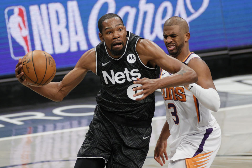 Kevin Durant of the Brooklyn Nets drives to the basket as Chris Paul of the Phoenix Suns defends 