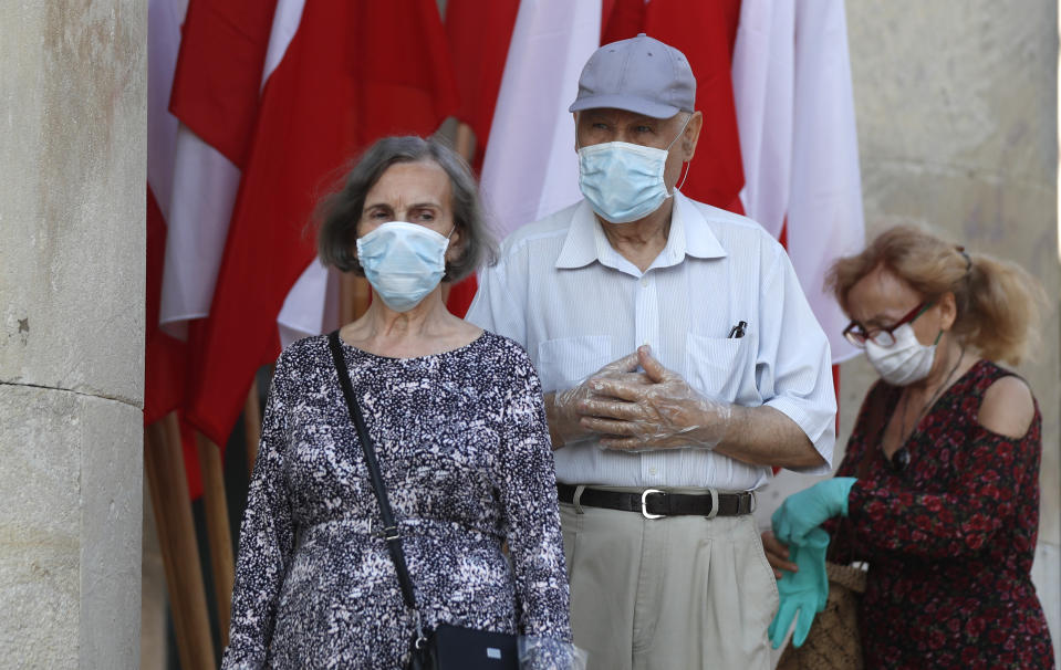 People, keeping social distancing, wait in line to cast their vote in the presidential election in Warsaw, Poland, Sunday, June 28, 2020. The election will test the popularity of incumbent President Andrzej Duda who is seeking a second term and of the conservative ruling party that backs him. (AP Photo/Petr David Josek)