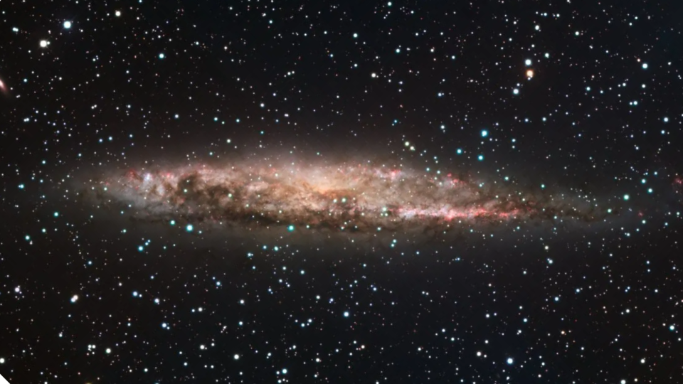 The galaxy NGC 4945 as seen by the European Southern Observatory's 2.2-meter telescope, with star formation sites visible in pink and the central AGN obscured by dust