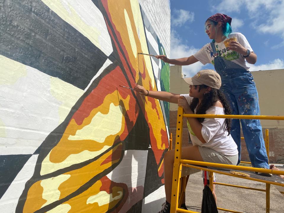Heaven Garrison, 17, (left) and Emily Quintanilla, 17, (right) touch up sections of a downtown mural Thursday.