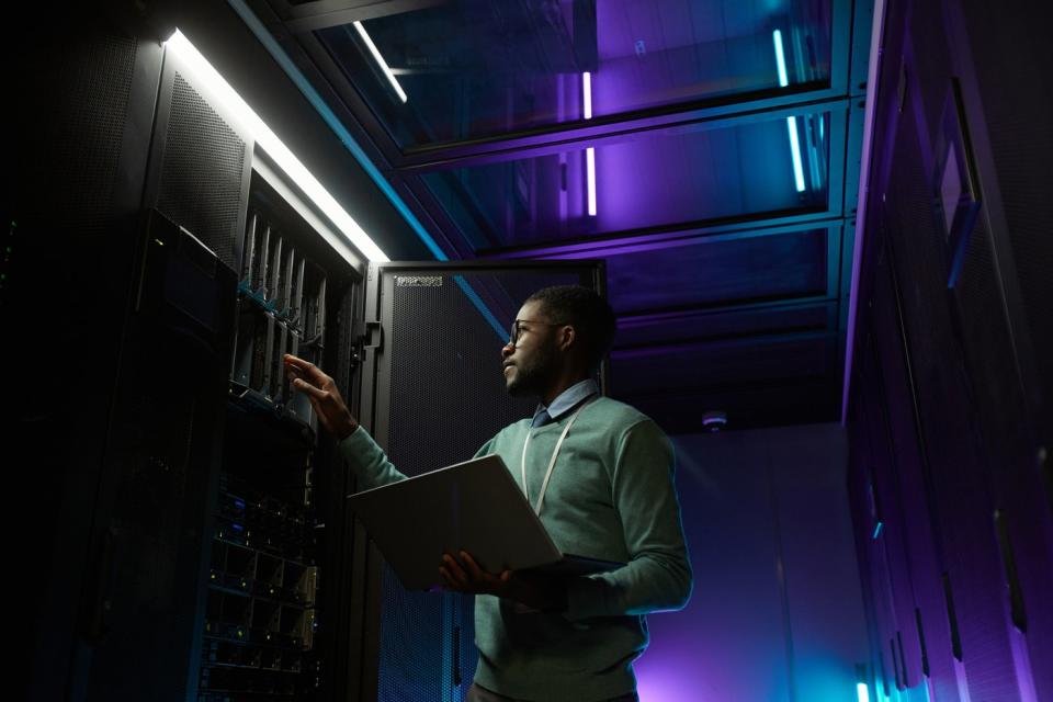 An IT professional checks a rack of servers in a data center.