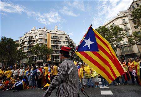 A man with a pro-independence Catalan flag walks in front of people forming a human chain to mark the "Diada de Catalunya" (Catalunya's National Day) in central Barcelona September 11, 2013. REUTERS/Albert Gea