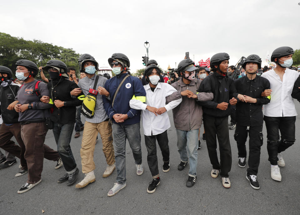 Anti-government protesters chain their arms as they march from Democracy Monument to government house in Bangkok, Thailand, Wednesday, Oct. 14, 2020. Anti-government protesters began gathering Wednesday for a planned rally at Bangkok's Democracy Monument being held on the anniversary of a 1973 popular uprising that led to the ousting of a military dictatorship, amid a heavy police presence and fear of clashes with political opponents. (AP Photo/Sakchai Lalit)