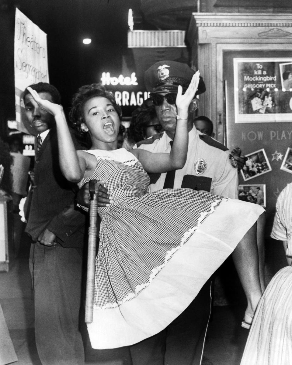 In a May 11, 1963, photograph, Knoxville College student Mariea Wooding is carried from the Tennessee Theatre by Knoxville Police Department Officer James Rowan during a civil rights protest. Standing at left is the late Avon Rollins.