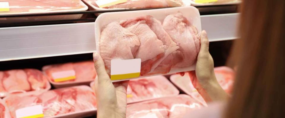 Woman choosing packed chicken meat in supermarket