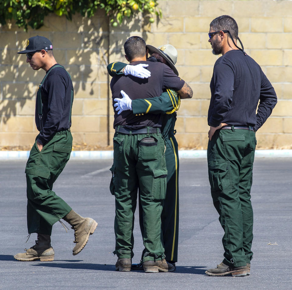 Members of the Big Bear Hotshots are embraced by one of the U.S. Forest Service pallbearers following the procession carrying fallen firefighter Charles Morton, killed while battling a blaze in the mountains east of Los Angeles, Tuesday, Sept. 22, 2020, from San Bernardino to the Ferrara Colonial Mortuary in Orange, Calif. Morton, 39, a San Diego native, was a 14-year veteran of the U.S. Forest Service and a squad boss for the Big Bear Interagency Hotshots in San Bernardino National Forest, officials said. (Mark Rightmire/The Orange County Register via AP)
