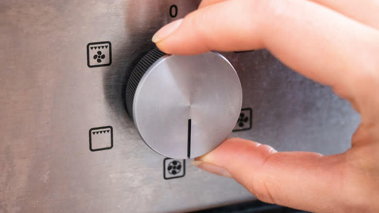 Hand turning dial on oven