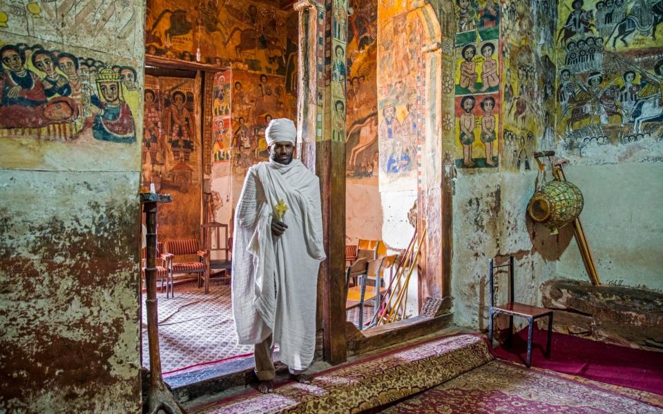 Orthodox priest inside Abreha We Atsbeha rock-hewn church decorated with medieval wall paintings near Wukro, Misraqawi Zone, Tigray Region - Arterra/Marica van der Meer/Universal Images Group via Getty Image