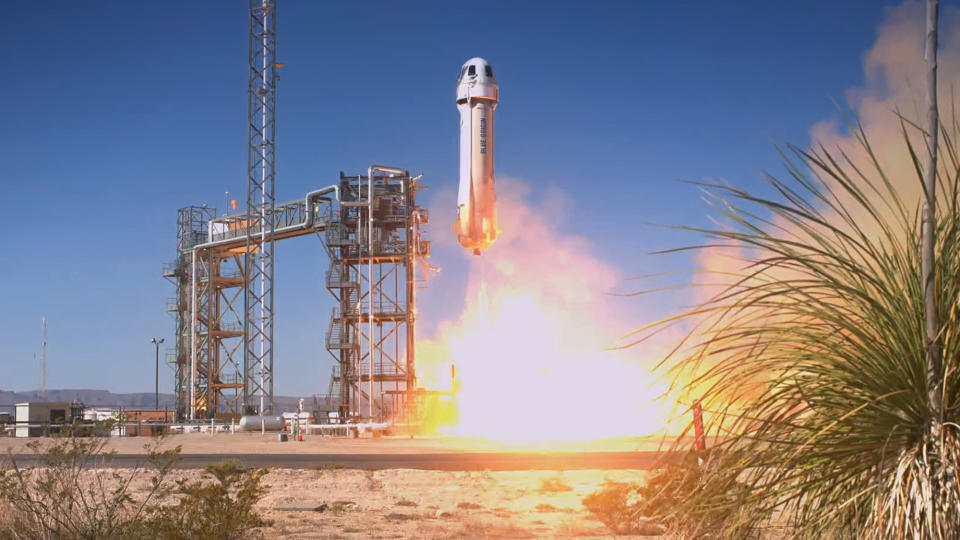  A white rocket launches into a blue sky, as seen from the ground. 