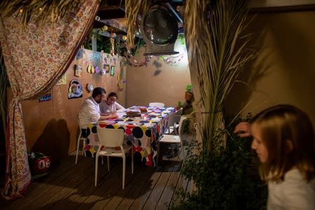 Yoni Stanleigh and his12 year old daughter Nehora sit in their sukka, or ritual booth, used during the Jewish holiday of Sukkot in their yard, in Jerusalem
