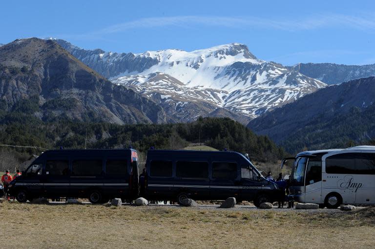 Gendarmerie vans block the view as relatives of Japanese victims pay their respects on March 29 2015 near a commemorative headstone in Seyne-les-Alpes