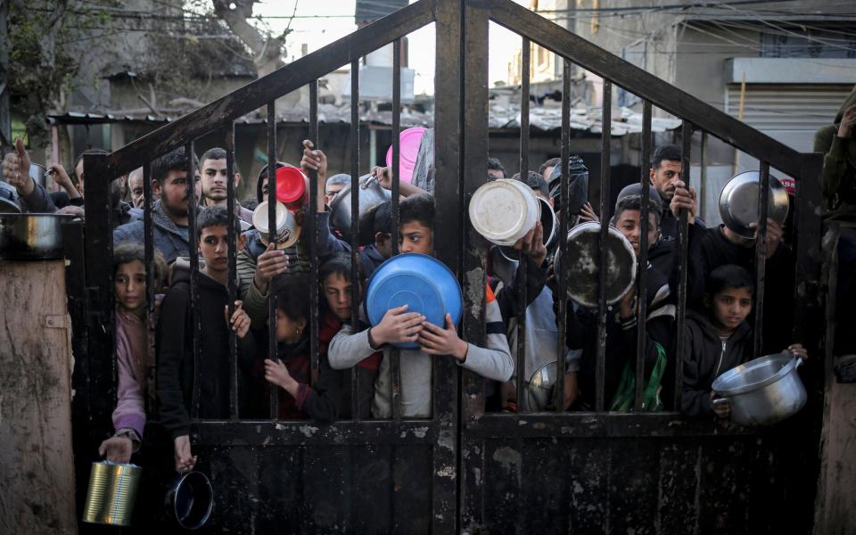 Displaced Palestinians gather to collect food donated by a charity before an iftar meal, the breaking of the fast, on the first day of the Muslim holy fasting month of Ramadan in Rafah, on the southern Gaza Strip on March 11, 2024