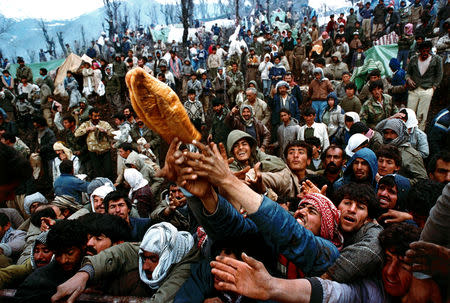 FILE PHOTO: Frantic Kurdish refugees struggle for a loaf of bread during a humanitarian aid distribution at the Iraqi-Turkish border, April 5, 1991. REUTERS/Yannis Behrakis/File photo