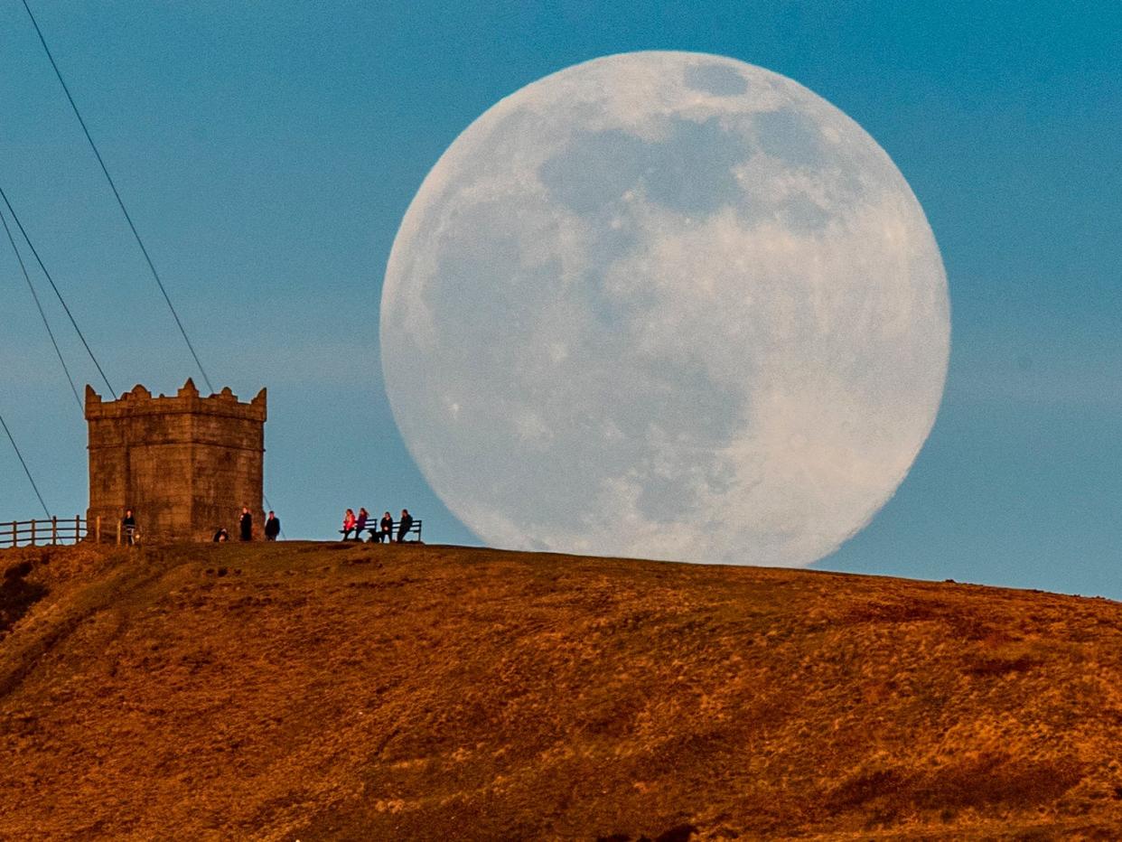 <p>The snow moon rises behind Rivington Pike near Bolton, Greater Manchester.</p> (PA)