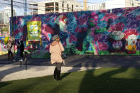 A woman looks at a mural at Wynwood Walls, Monday, Nov. 15, 2021, in Miami. Cooped-up tourists eager for a taste of Florida's sandy beaches, swaying palm trees and warmer climates are visiting the Sunshine State in droves, topping pre-pandemic levels in recent months. (AP Photo/Lynne Sladky)