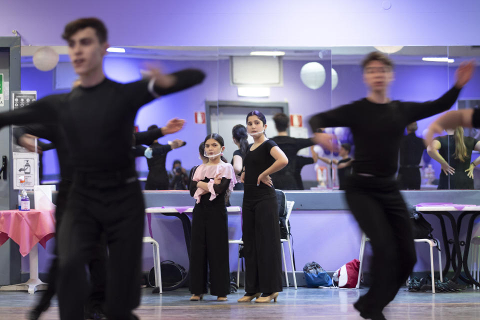 Dancers, wearing face masks to curb the spread of COVID-19 look at their schoolmates training at the New Dancing Days School, in Rome, Wednesday March 24, 2021. While much of Italy is in coronavirus lockdown, with live music and theatrical performances barred, cinemas shuttered and many sporting activities limited, competitive ballroom dancing is alive and well here, albeit with precautions. (AP Photo/Alessandra Tarantino)