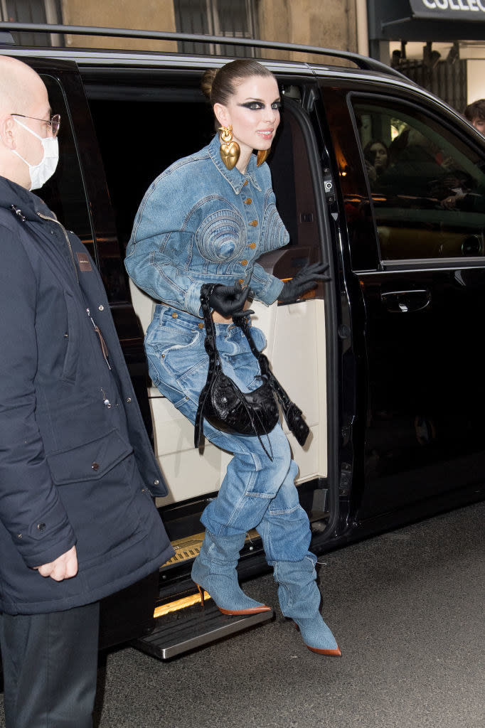 Big hoop earrings, short jean jacket with cone-shaped breast pieces, jeans, and stiletto jean boots