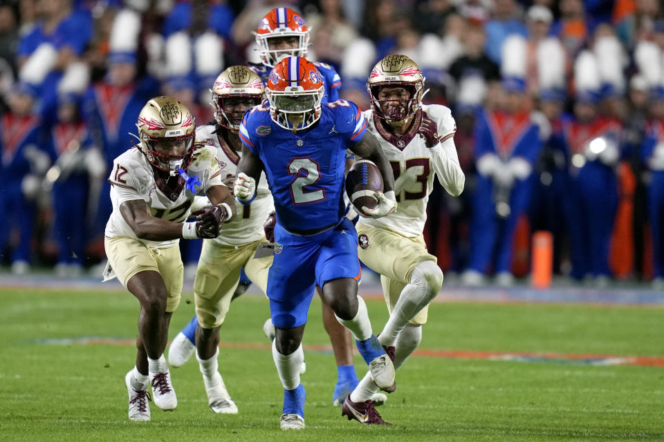 Florida running back Montrell Johnson Jr. (2) outruns Florida State defensive back Conrad Hussey (12), defensive back Akeem Dent, back center, and defensive back Fentrell Cypress II, right, on a 52-yard run during the first half of an NCAA college football game Saturday, Nov. 25, 2023, in Gainesville, Fla. (AP Photo/John Raoux)
