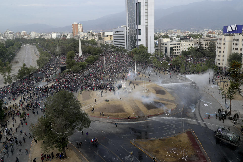 Police and demonstrators clash during an anti-government protest in Santiago, Chile, Monday, Nov. 4, 2019. Thousands of Chileans took to the streets again Monday to demand better social services, some clashing with police, as protesters demanded an end to economic inequality even as the government announced that weeks of demonstrations are hurting the country's economic growth. (AP Photo/Esteban Felix)