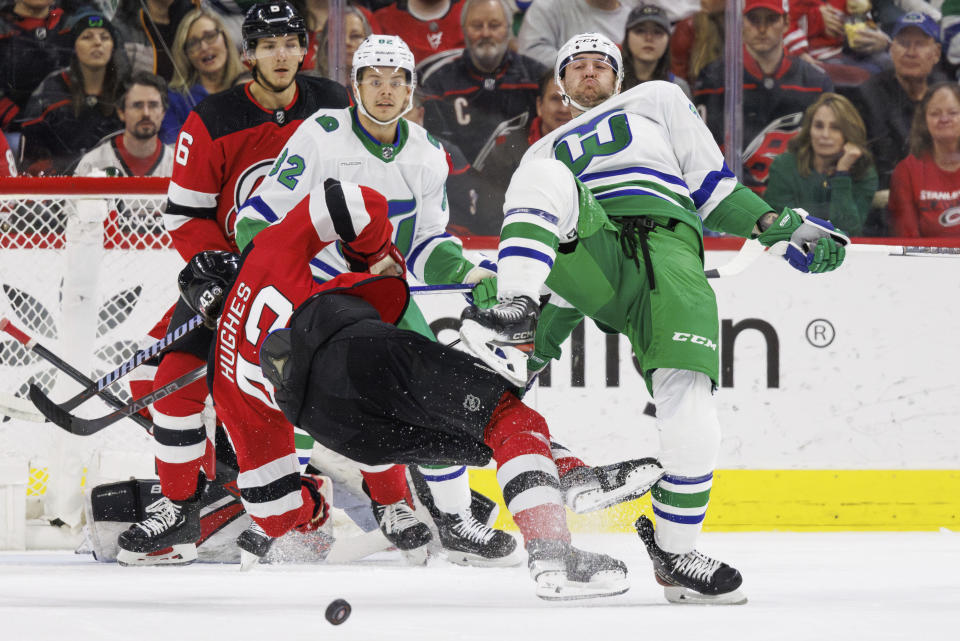 Carolina Hurricanes' Stefan Noesen, right, collides with New Jersey Devils' Luke Hughes (43) ahead of Carolina Hurricanes' Jesperi Kotkaniemi (82) and New Jersey Devils' John Marino (6) during the first period of an NHL hockey game in Raleigh, N.C., Saturday, Feb. 10, 2024. (AP Photo/Ben McKeown)