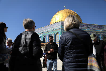 The tour guide, Noor Awad, a Palestinian from Bethlehem, speaks to tourists, during the Dual Narrative tour he leads together with his colleague Lana Zilberman Soloway, a Jewish seminary student, next to the Dome of the Rock on the compound known to Jews as Temple Mount and Muslims as The Noble Sanctuary in Jerusalem's Old City February 4, 2019. REUTERS/Ammar Awad/Files