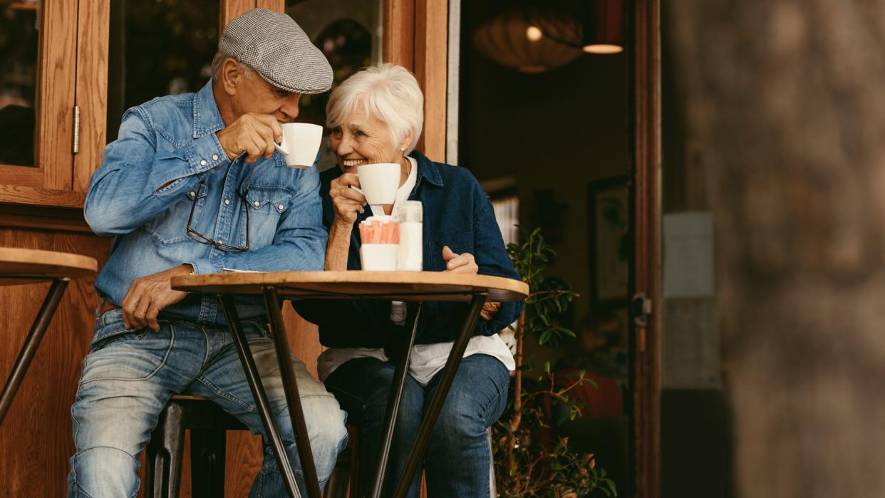 Happy senior couple sitting at coffee shop and talking.