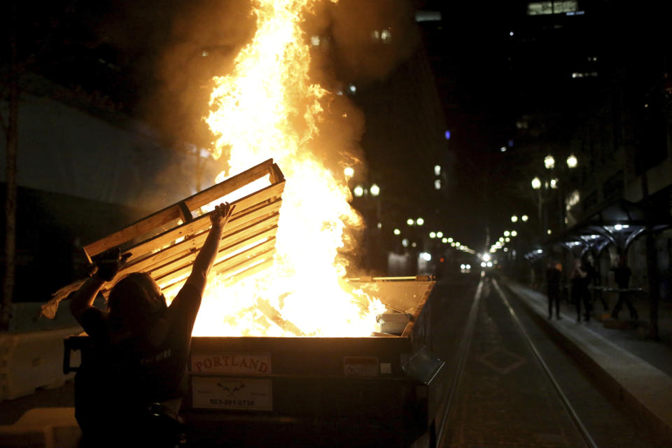 Protesters light a fire in a dumpster in downtown Portland, Ore., Friday, April 16, 2021. Police in Portland, said Saturday they arrested several people after declaring a riot Friday night when protesters smashed windows, burglarized businesses and set multiple fires during demonstrations that started after police fatally shot a man while responding to reports of a person with a gun. (Dave Killen/The Oregonian via AP)