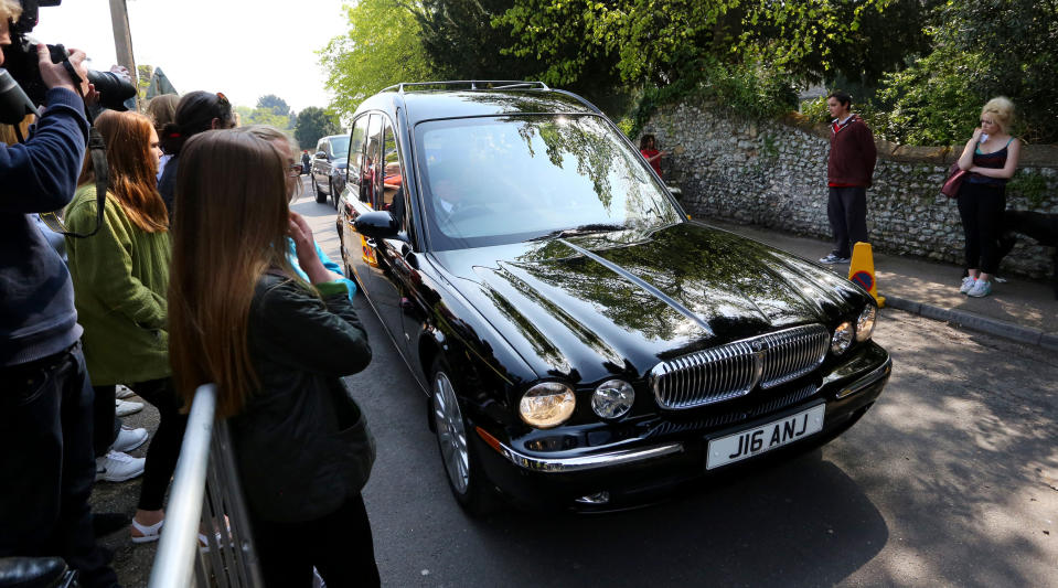 A small crowd watch the coffin of late Peaches Geldof, the daughter of rock singer Sir Bob Geldof, arrive at his home ahead of her funeral service at St Mary Magdalene and St Lawrence Church in Davington, near Faversham, England, Monday April 21, 2014. The 25-year-old television presenter, model and socialite, Peaches Geldof died suddenly two weeks ago at her home, and the cause of death is not yet known after a post-mortem was inconclusive, and toxicology test results are not yet complete. The coffin is adorned with a painted picture of Peaches Geldof, her husband Thomas Cohen, their two young sons Astala, 23 months, and 11-month-old Phaedra, and pet dogs. (AP Photo / Gareth Fuller, PA) UNITED KINGDOM OUT - NO SALES - NO ARCHIVES