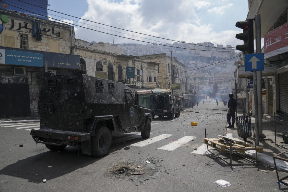 Palestinians clash with Palestinian security forces following an arrest raid against local militants, in the West Bank city of Nablus Tuesday, Sept. 20, 2022. Palestinian security forces on Tuesday exchanged fire with militants in the center of the West Bank's second-largest city, as angry residents pelted an armored jeep with objects and chased it away. One man was reported dead. The incident marked a rare case of deadly internal Palestinian fighting in the occupied West Bank. (AP Photo/Nasser Nasser)