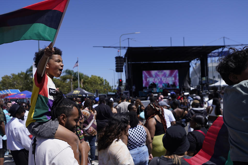 FILE - Julien James carries his son, Maison, 4, holding a Pan-African flag to celebrate during a Juneteenth commemoration at Leimert Park in Los Angeles Saturday, June 18, 2022. Many Americans are celebrating Juneteenth, marking the day in 1865 when the last enslaved people in the U.S. learned they were free. For generations, Black Americans have recognized the end of one of history’s darkest chapters with joy, in the form of parades, street festivals, musical performances or cookouts. (AP Photo/Damian Dovarganes, File)