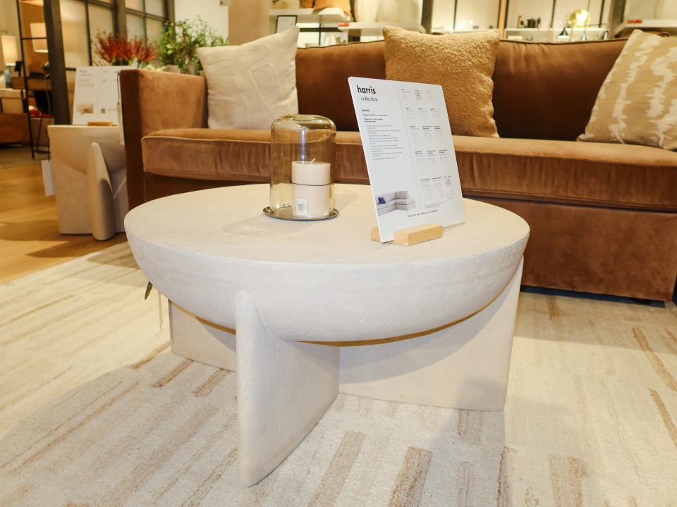 A white table with a semicircle design and an orange couch with tan pillows in the background