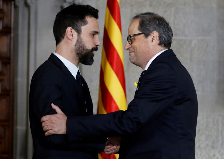 El nuevo presidente de Cataluña, Quim Torra (d), estrecha la mano del presidente del Parlamento regional, Roger Torrent, tras su toma de posesión oficial el 17 de mayo de 2018 en Barcelona