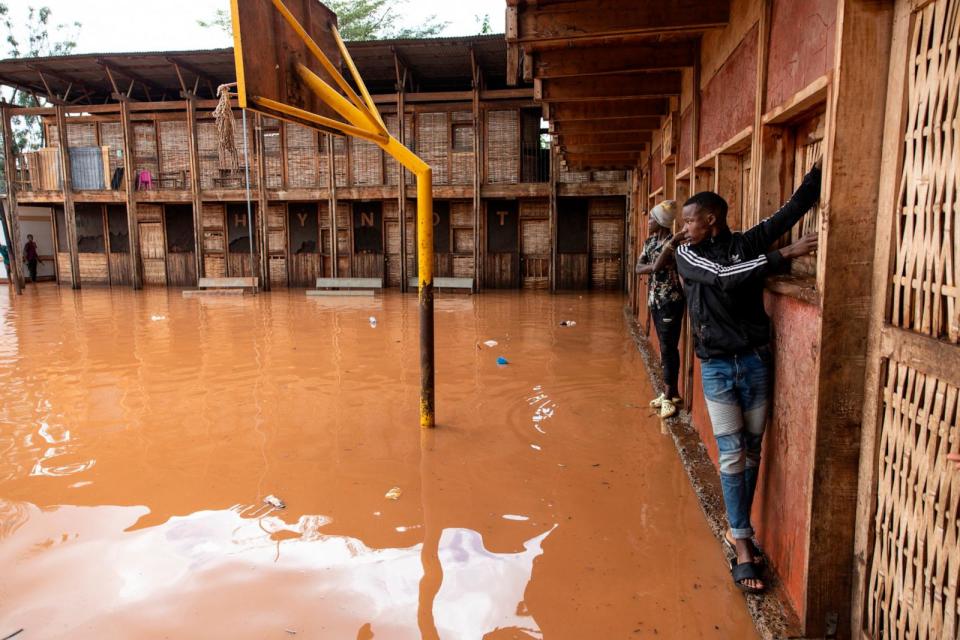 PHOTO: Residents of Mathare slum use the wall to cross a flooded school field, following heavy down pour in the capital, Nairobi on April 24, 2024. (Simon Maina/AFP via Getty Images)