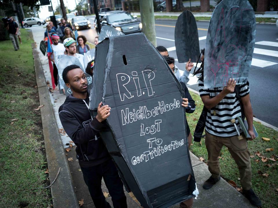 Demonstrators march with signs during a "funeral procession for gentrified neighborhoods" near Fisk University, Thursday, Nov. 2, 2017, in Nashville, Tenn.